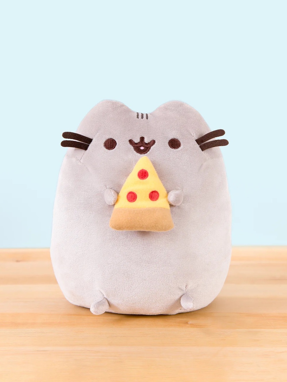 Pusheen holding a pizza plush